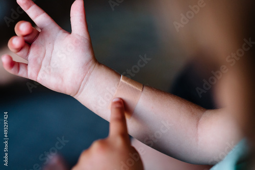 little kid points at bandage on arm photo
