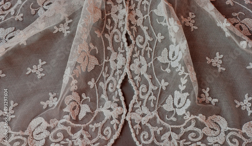 Spanish lace veil, mantilla, shawl or covering draped with traditional old design showing floral motif in delicate net pattern. This is a closeup of threads in white.
