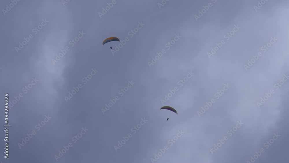 Two paragliders flying through the stormy clouds. Extreme sports activities in winter concept. Slow motion. Two paragliders flying through the stormy clouds. Extreme sports activities in winter concept. Slow motion.