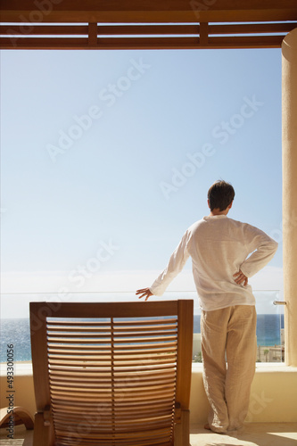 Man on vacation on balcony of resort hotel room photo