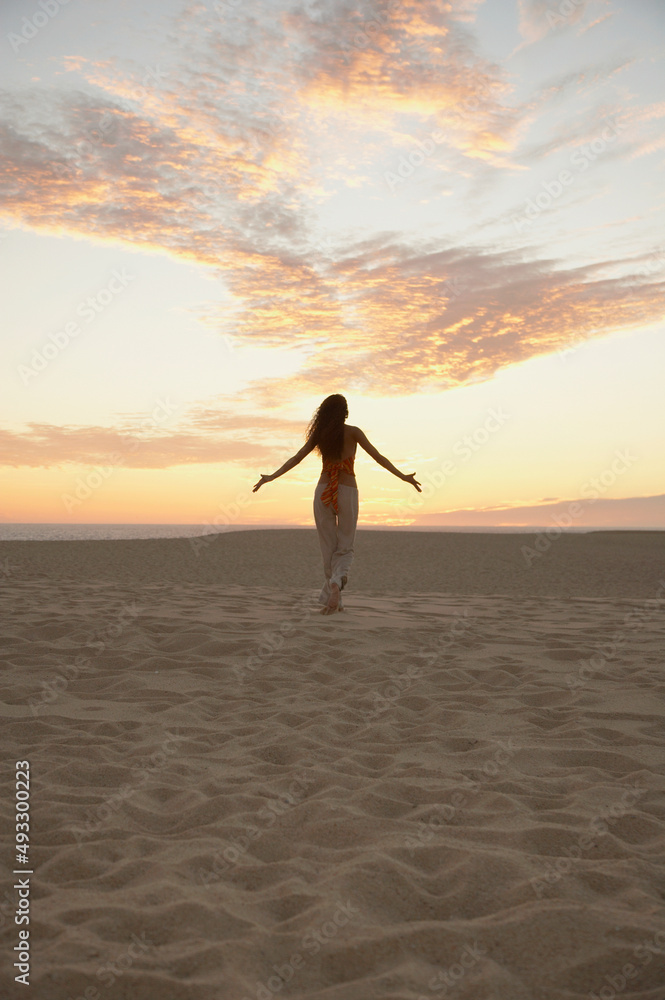 Woman walking on beach with arms open and extended Woman walking on beach with arms open and extended