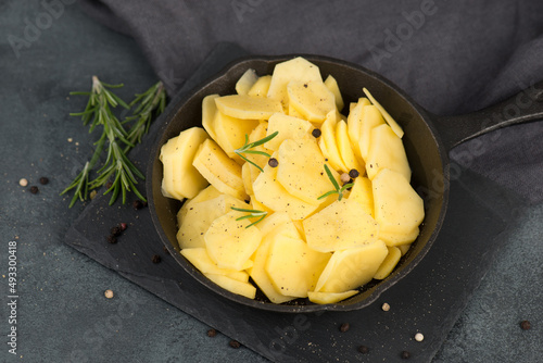 Sliced potatoes in a pan with rosmarine, pepper and olive oil, healthy vegetarian food
 photo