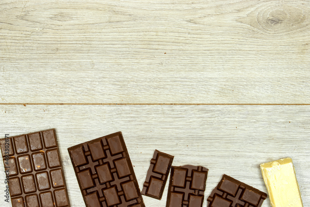 milk and black, white chocolate bars on wood table milk and black, white chocolate bars on wood table