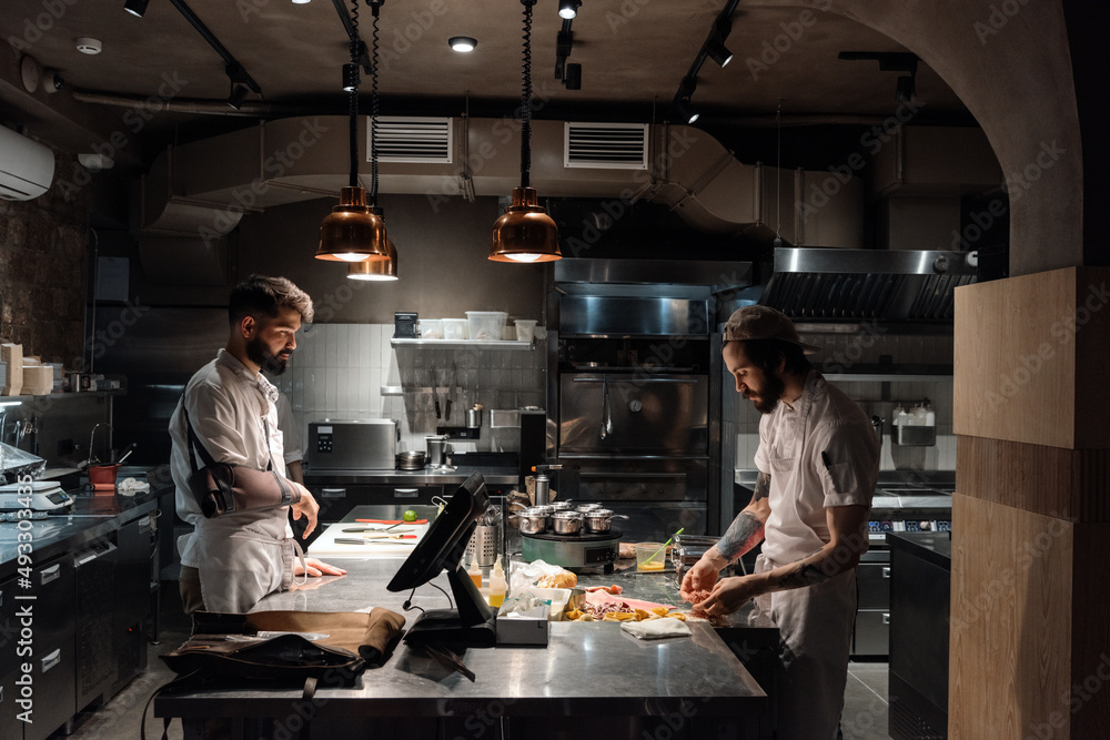 Male chef watching working colleague Male chef watching working colleague