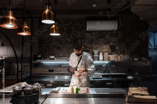 Male chef picking ingredients from plastic box photo