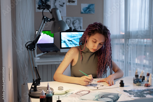 Young female illustrator drawing picture with ink photo