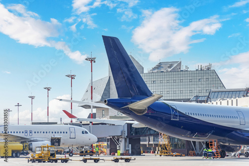 Aircraft in pre-flight maintenance and their tails at the airport next to the passenger terminal.