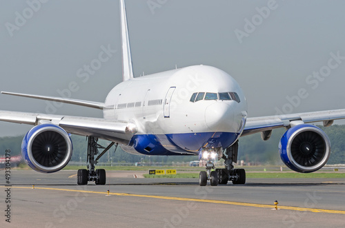 White passenger airplane rides the track taxiway at the airport.