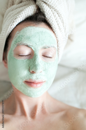 Young woman with green clay cosmetic mask on her face - skincare and spa treatment beauty routine, relaxing moments
