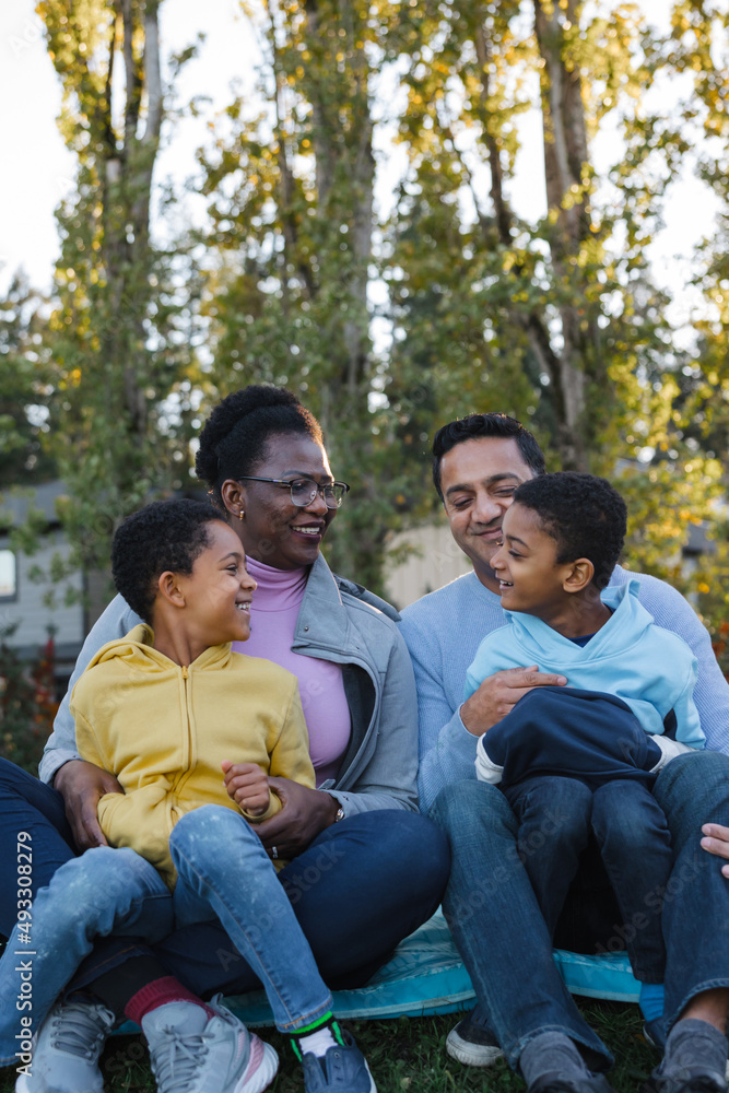 Family enjoys sitting on blanket together outside. Family enjoys sitting on blanket together outside.