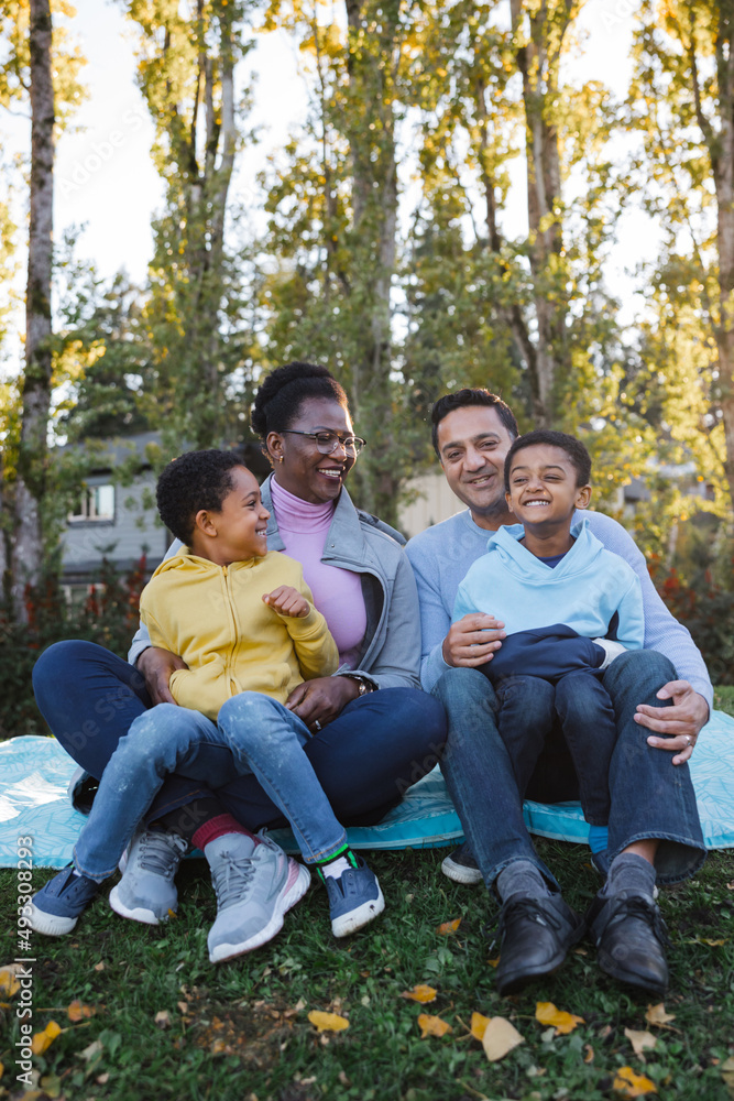 Family enjoys sitting on blanket together outside. Family enjoys sitting on blanket together outside.