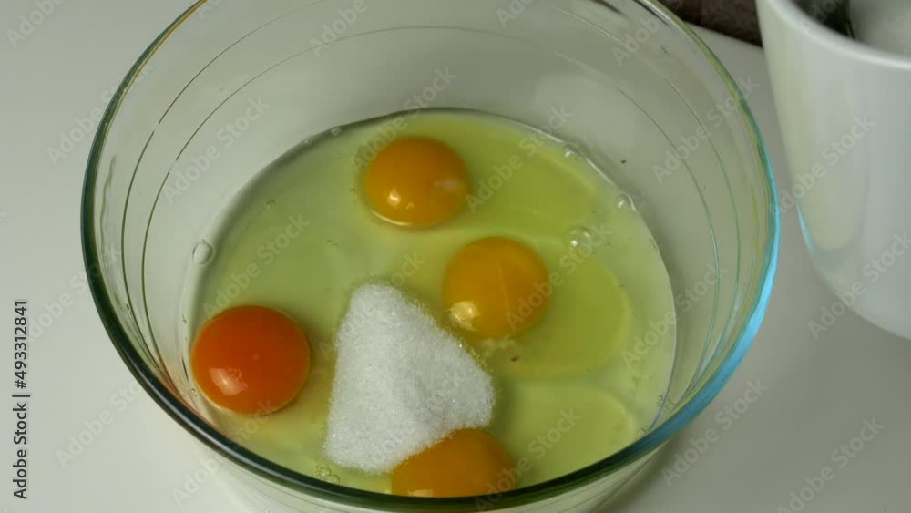 Woman adds spoons of sugar together with four eggs in glass bowl for the preparation of typical Piedmontese dessert. Slow motion 4K Woman adds spoons of sugar together with four eggs in glass bowl for the preparation of typical Piedmontese dessert. Slow motion 4K