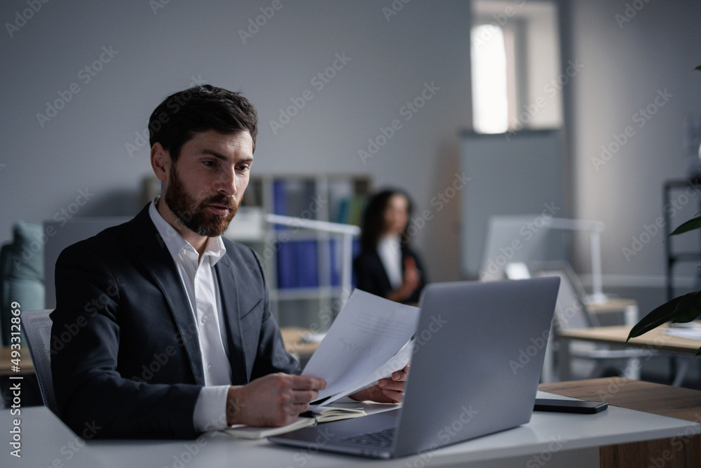 Male analyst browsing documents and report Male analyst browsing documents and report