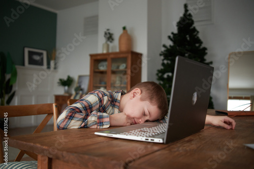Boy Student Tired in front of Laptop Computer at Home. photo