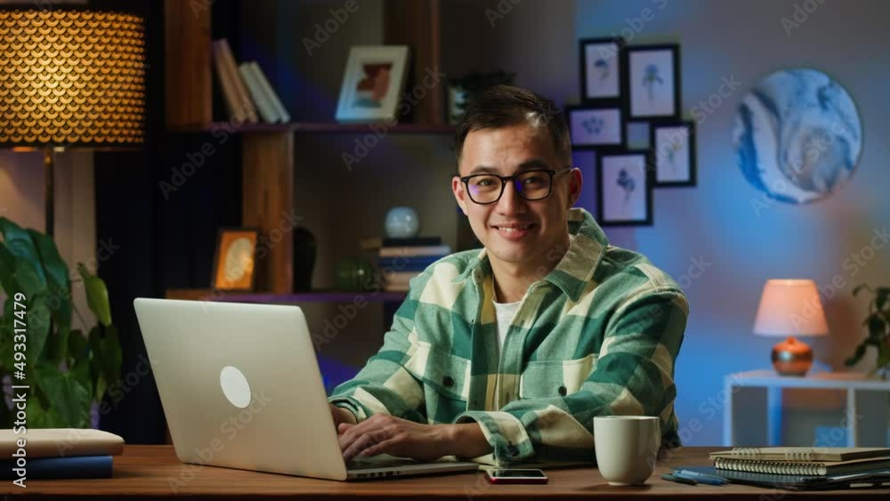 Asian man portrait, typing on laptop, sitting in living room. Korean young guy working remotely at home during coronavirus lockdown. Businessman using computer for remote work, freelance. Asian man portrait, typing on laptop, sitting in living room. Korean young guy working remotely at home during coronavirus lockdown. Businessman using computer for remote work, freelance.