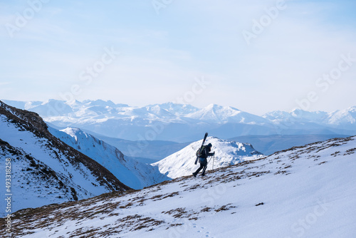 a woman is carrying her skis  for backcountry skiing photo