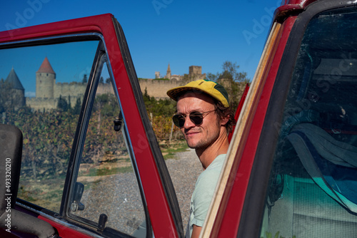 A lonely traveler guy at his window in his camper van by a beautiful old caste 