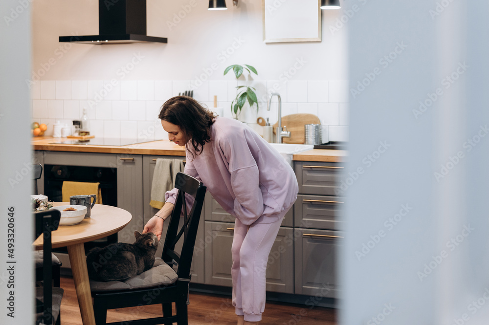 Woman petting cat in kitchen Woman petting cat in kitchen