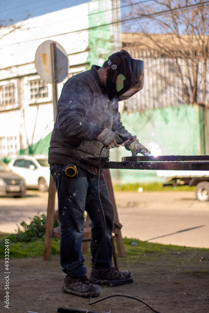 Welder welding a grating wearing a welder helmet with a beautiful welding flash	