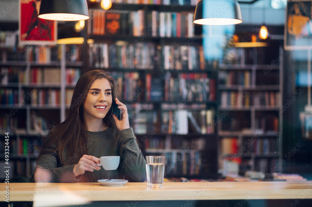 Woman using smartphone and drinking coffee in a cafe. Woman using smartphone and drinking coffee in a cafe.