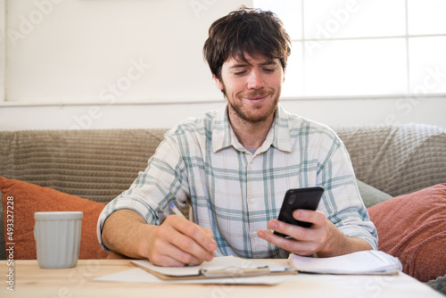 Portrait of man doing finances with phone and notebook photo