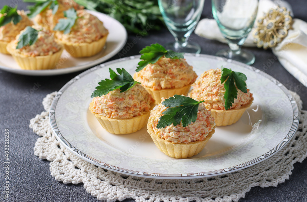 Tartlets with cheese, chicken and carrots garnished with parsley on dark gray background Tartlets with cheese, chicken and carrots garnished with parsley on dark gray background