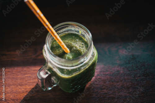 jar with green cold-pressed juice, wooden background. Healthy eating, detoxing, juicing, body cleancing concept photo