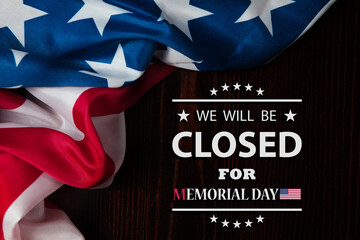 Memorial Day Background Design. American flag on a background of wooden teable with a message. We will be Closed for Memorial Day.