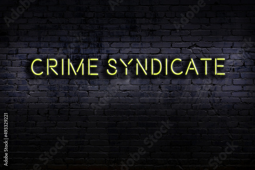 Night view of neon sign on brick wall with inscription crime syndicate