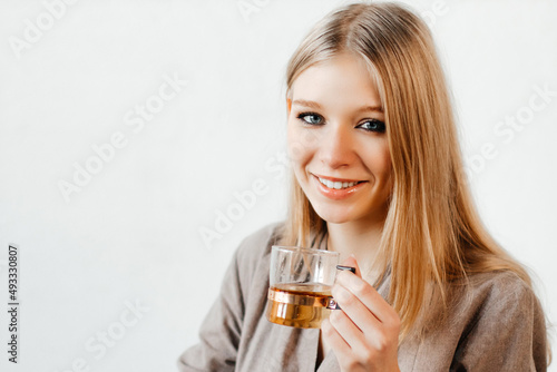 Attractive smiling girl is drinking herbal tea. Young woman is enjoying tasty drink. Concept of cafe