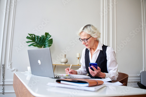 Mature woman accountant counts taxes, photo