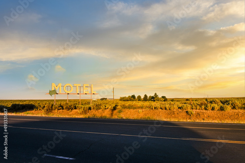 A vintage generic Motel roadside sign in the high desert of Eastern Washington, USA, with a small ranch in the distance on a late summer day. 