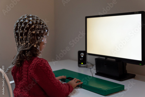 Kid in EEG cap looking at monitor in laboratory photo