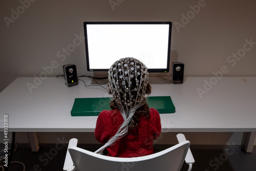 Kid in EEG cap looking at monitor in laboratory photo