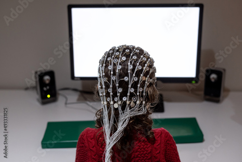 Child in EEG cap looking at monitor in laboratory photo