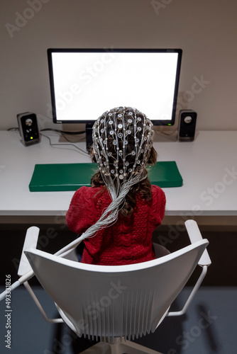 Girl in EEG cap looking at monitor in laboratory photo