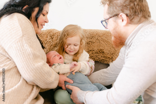 mom and dad handing newborn to big sister  photo