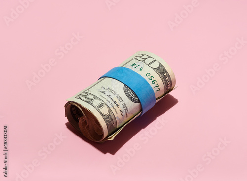 Roll of $20 USA Bills on Pink Background  