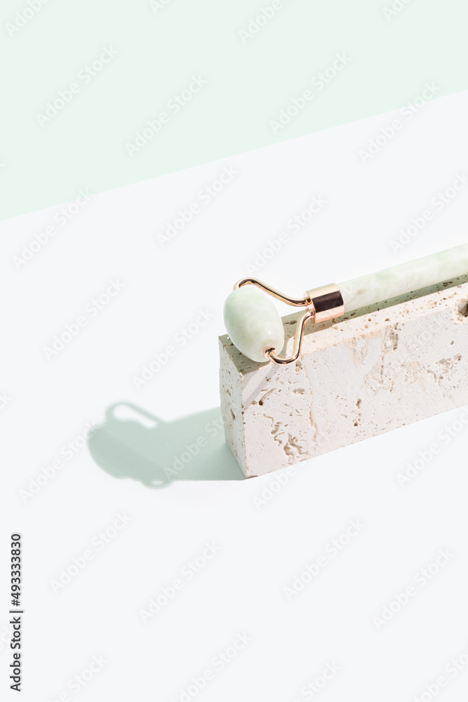 Jade roller on mint and white background