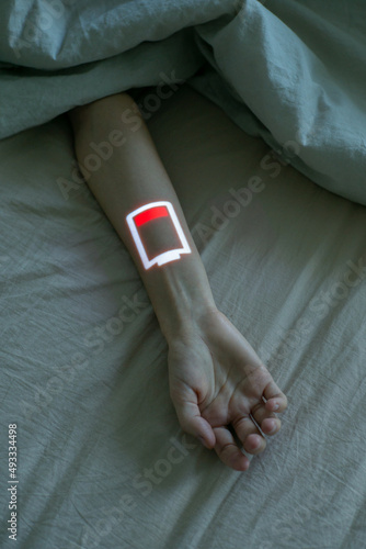 Rest in bed. Human hand with low battery symbol photo