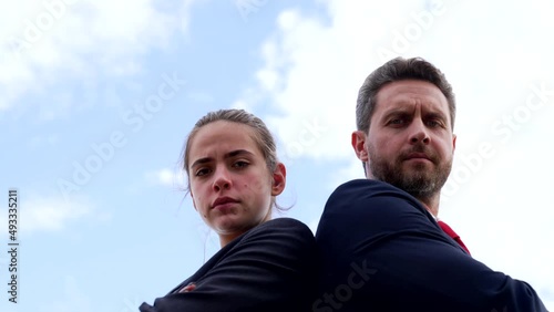 Professional couple of serious man and frown woman stand keeping arms crossed on sky, colleagues photo