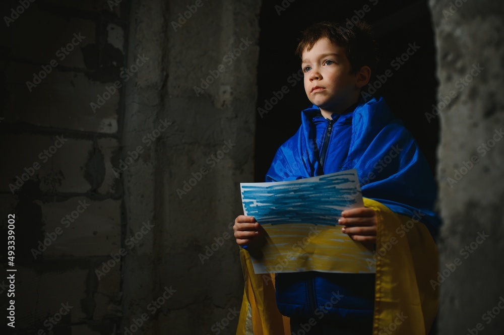 Ukrainian Crying boy holds a painted flag of Ukraine. War of Russia against Ukraine. Ukrainian Crying boy asks to stop the war in Ukraine. Child with message Stop War. Ukrainian Crying boy holds a painted flag of Ukraine. War of Russia against Ukraine. Ukrainian Crying boy asks to stop the war in Ukraine. Child with message Stop War.