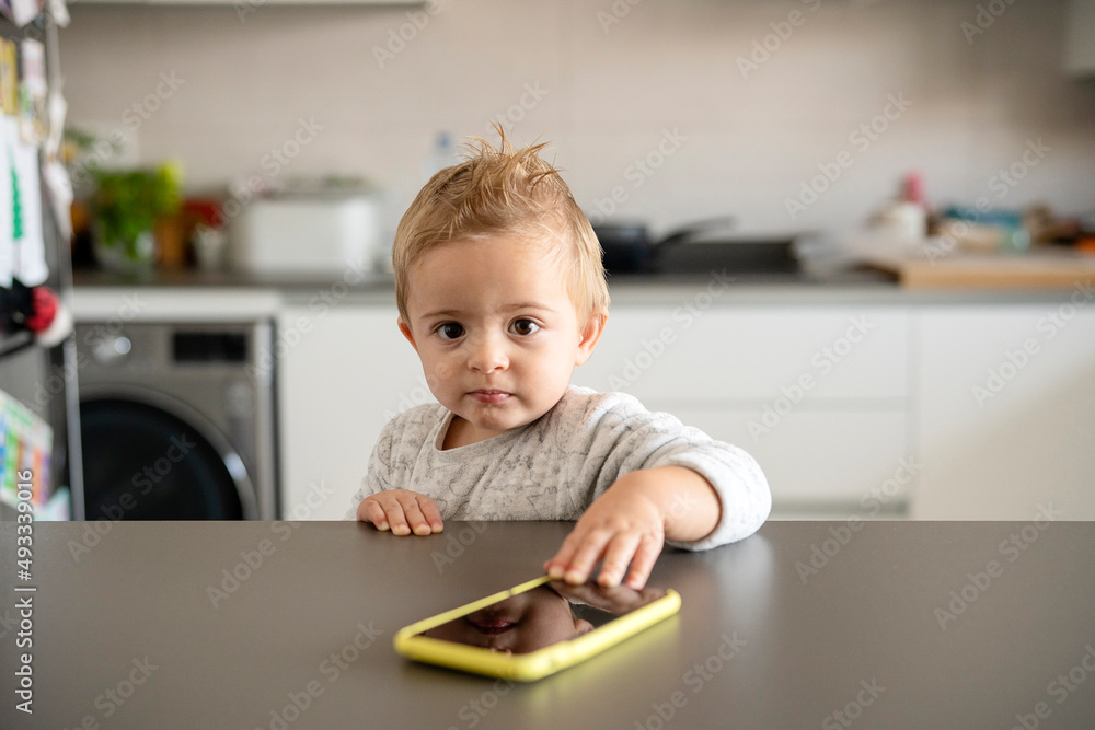 Toddler with smartphone looking at camera Toddler with smartphone looking at camera