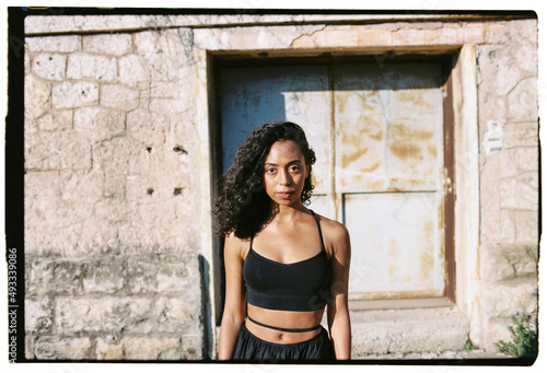 Fit woman in black outfit standing near old building