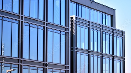 Minimalist glass facade  steel framework holding the large transparent panels. Contemporary commercial architecture  vertical converging geometric lines. Blue sky reflection in the glass panels