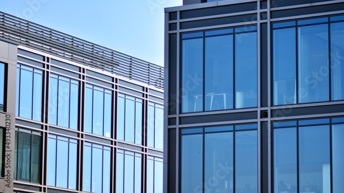 Minimalist glass facade  steel framework holding the large transparent panels. Contemporary commercial architecture  vertical converging geometric lines. Blue sky reflection in the glass panels