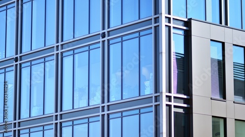 Minimalist glass facade  steel framework holding the large transparent panels. Contemporary commercial architecture  vertical converging geometric lines. Blue sky reflection in the glass panels