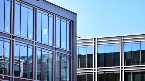 Minimalist glass facade  steel framework holding the large transparent panels. Contemporary commercial architecture  vertical converging geometric lines. Blue sky reflection in the glass panels