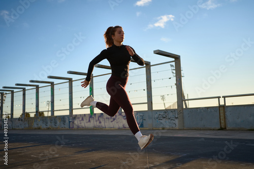 Woman jogger running along bridge in sunlight photo