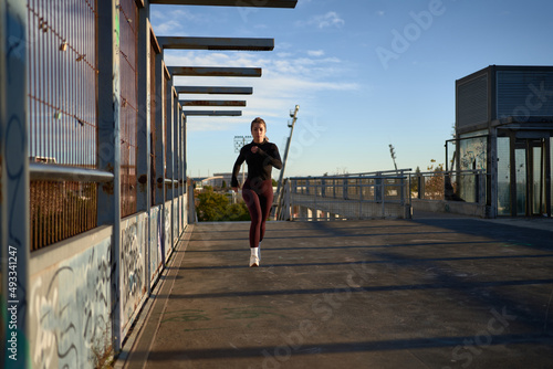 Woman jogger running along bridge in sunlight photo